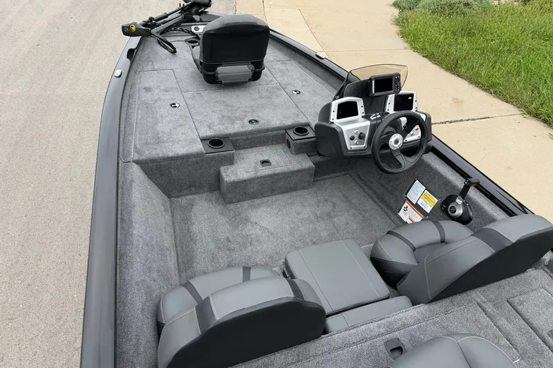 Slide: The Image of 2026 Tracker Pro Team 175 boat interior with steering console and seating, parked on pavement. - 16