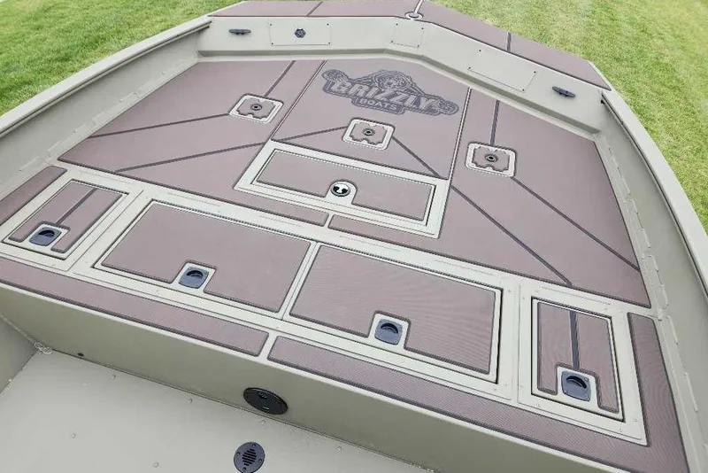 Slide: The Image of 2026 Tracker Grizzly 2072 CC boat deck with storage compartments and logo. - 51