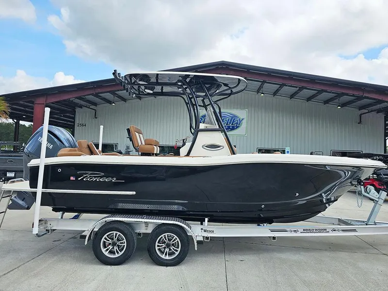 The Image of 2025 Pioneer 222 Islander boat on trailer, parked outside a metal building under a cloudy sky. - 1