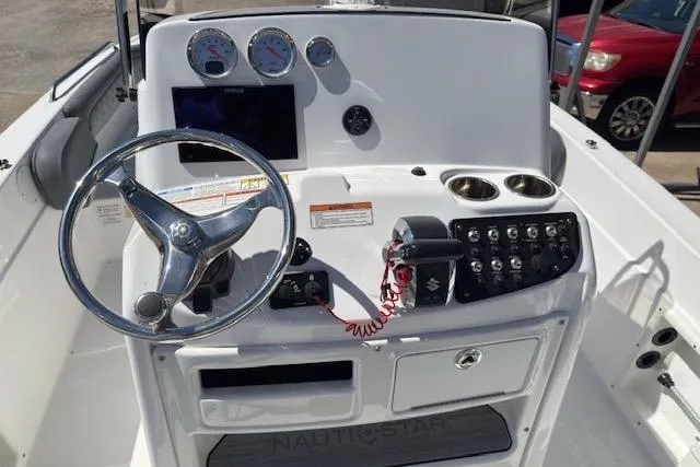 Slide: The Image of 2024 NauticStar 211 Hybrid boat dashboard with steering wheel, gauges, and control panel. - 6