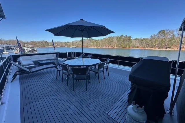 Slide: The Image of Deck of 1999 Sumerset 18x82 houseboat with seating, umbrella, and grill by the water. - 16