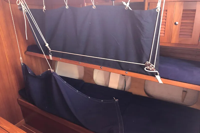 Slide: The Image of Interior of 2004 J Boats J/133 sailboat with wooden cabinetry and navy blue canvas bunks. - 14