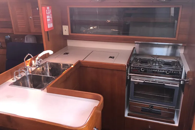 Slide: The Image of Galley of 2004 J Boats J/133 with stove, sink, and wooden cabinetry. - 15