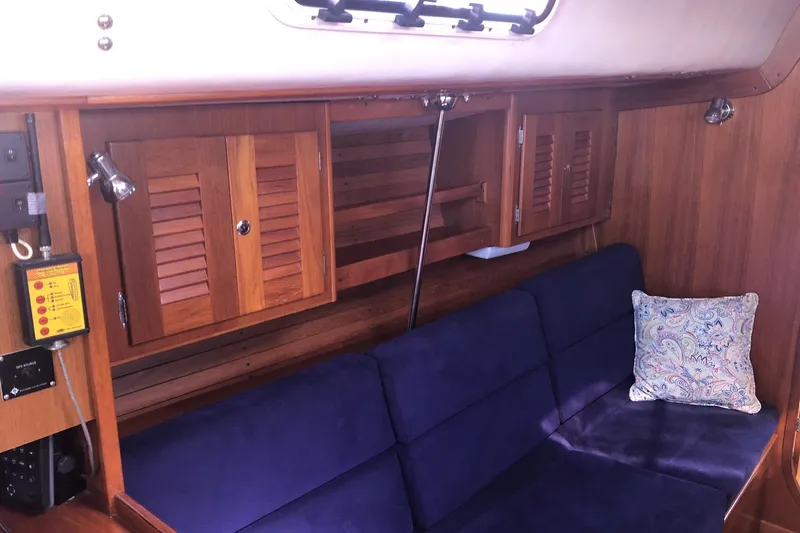 Slide: The Image of Interior of 2004 J Boats J/133 with blue seating, wooden cabinets, and decorative pillow. - 8