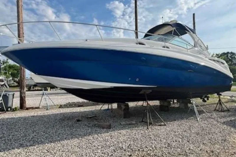 Slide: The Image of 2005 Sea Ray Sundancer 320 boat on stands, blue hull, outdoor setting. - 1