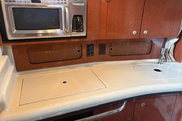 Slide: The Image of Interior of a 2005 Sea Ray Sundancer 320 yacht, featuring a kitchenette with microwave and sink. - 23