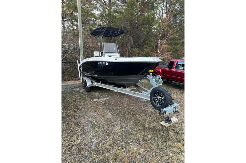 The Image of 2019 Yamaha Boats 210 FSH Sport on trailer, parked outdoors near trees. - 0