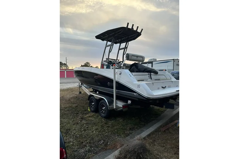 Slide: The Image of 2019 Yamaha Boats 210 FSH Sport on trailer, parked outdoors at sunset. - 2