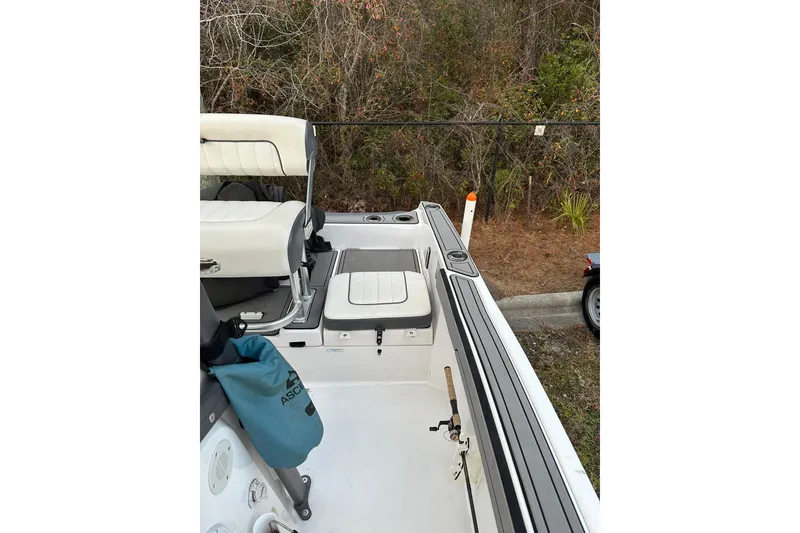 Slide: The Image of 2019 Yamaha Boats 210 FSH Sport interior with seating and storage, parked near foliage. - 22