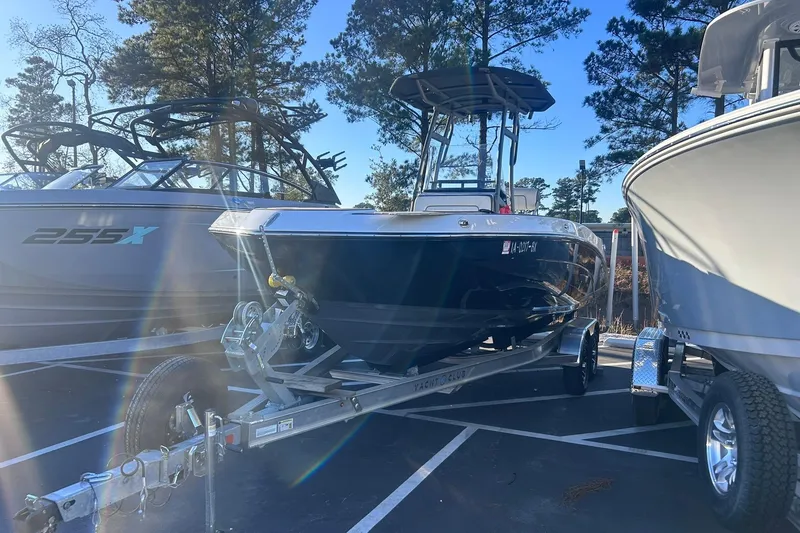 Slide: The Image of 2019 Yamaha Boats 210 FSH Sport on trailer, parked outdoors with other boats. - 4