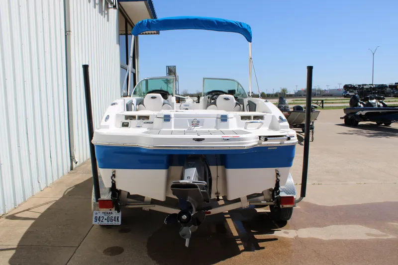 Slide: The Image of 2021 Chaparral 19 SSi Ski & Fish boat with blue and white exterior, parked outdoors. - 22