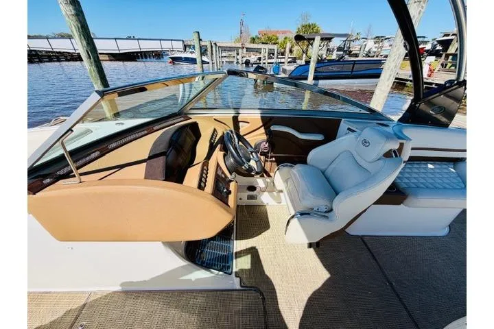 Slide: The Image of 2017 Cobalt R7 boat interior with steering wheel, white seating, and dockside view. - 14
