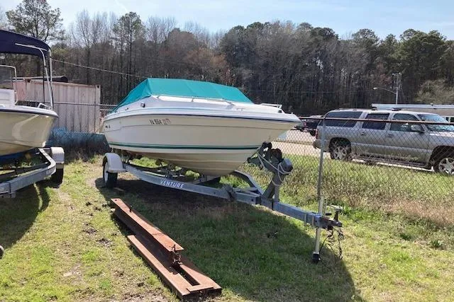 The Image of 1990 Searay 200 Cuddy boat on trailer, parked outdoors near a fence. - 0