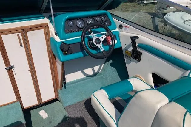 Slide: The Image of 1990 Searay 200 Cuddy boat interior with teal and white seating and dashboard. - 2