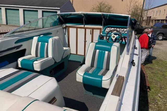 Slide: The Image of 1990 Searay 200 Cuddy boat interior with teal and white seating, parked outdoors. - 5
