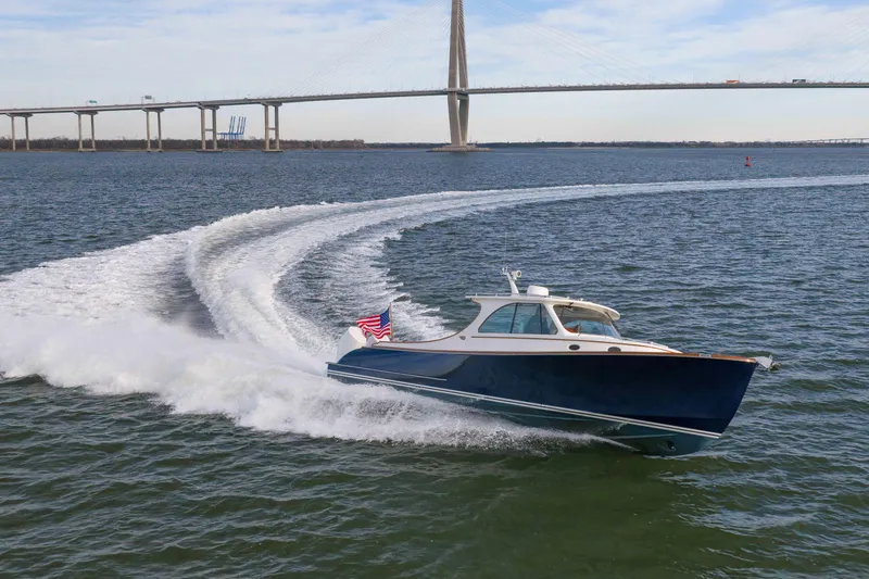 Slide: The Image of 2024 Hinckley 35 cruising on water near a bridge, showcasing sleek design and performance. - 11