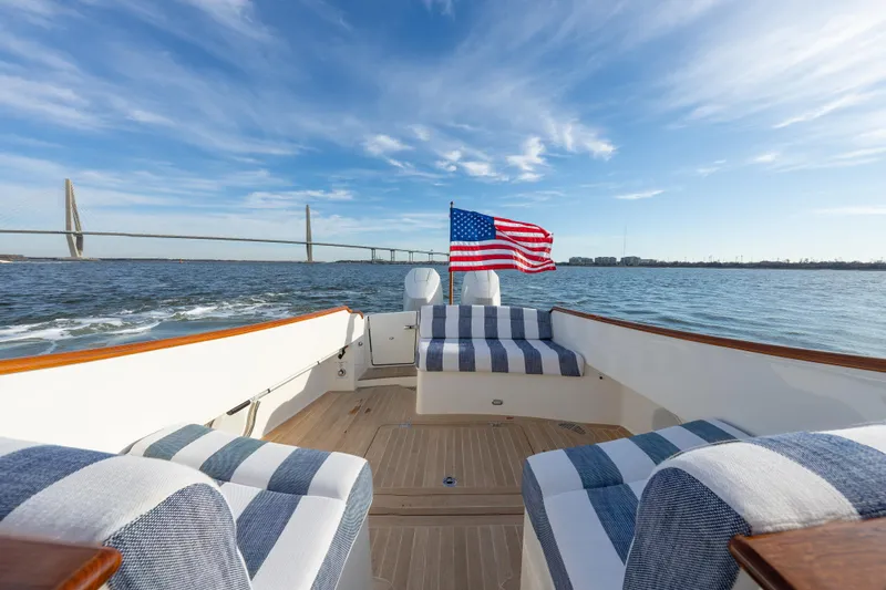 Slide: The Image of 2024 Hinckley 35 boat with American flag, cruising near a bridge under a clear blue sky. - 12
