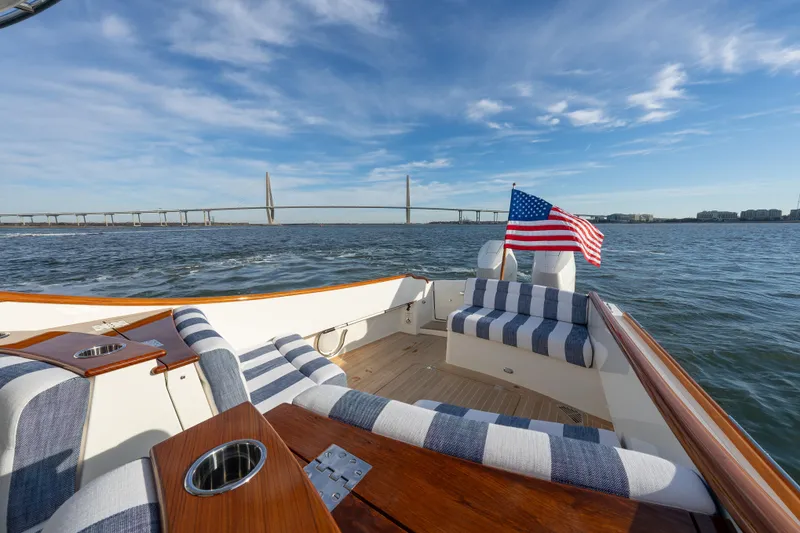 Slide: The Image of Hinckley 35 yacht deck with striped seating, American flag, and scenic bridge view, 2024 model. - 13