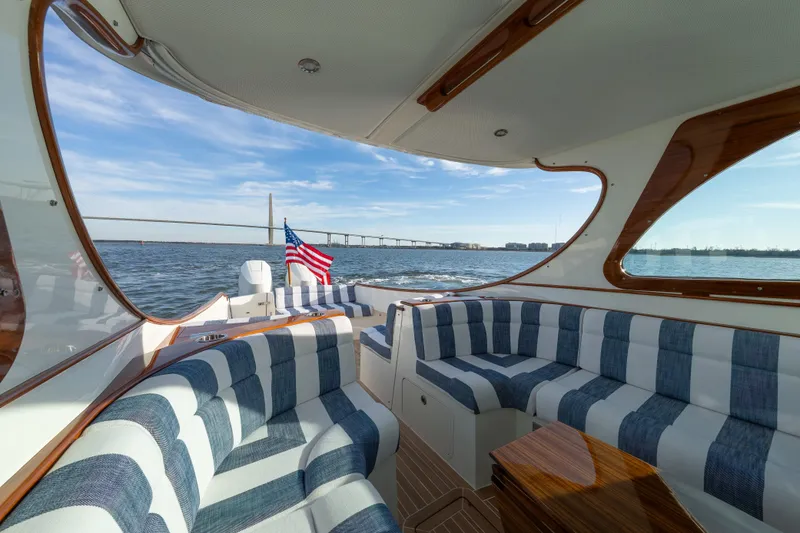 Slide: The Image of Luxurious 2024 Hinckley 35 yacht interior with striped seating, American flag, and scenic water view. - 14