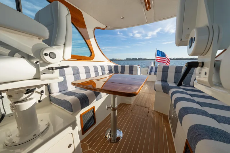 Slide: The Image of Interior of 2024 Hinckley 35 yacht with striped seating and wooden table, overlooking water. - 16