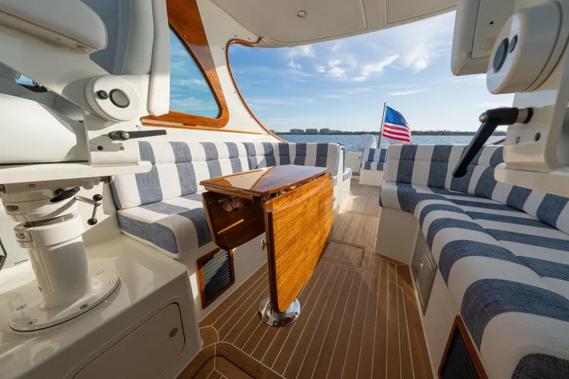 Slide: The Image of Luxurious 2024 Hinckley 35 yacht interior with striped seating and wooden table, overlooking serene waters. - 17