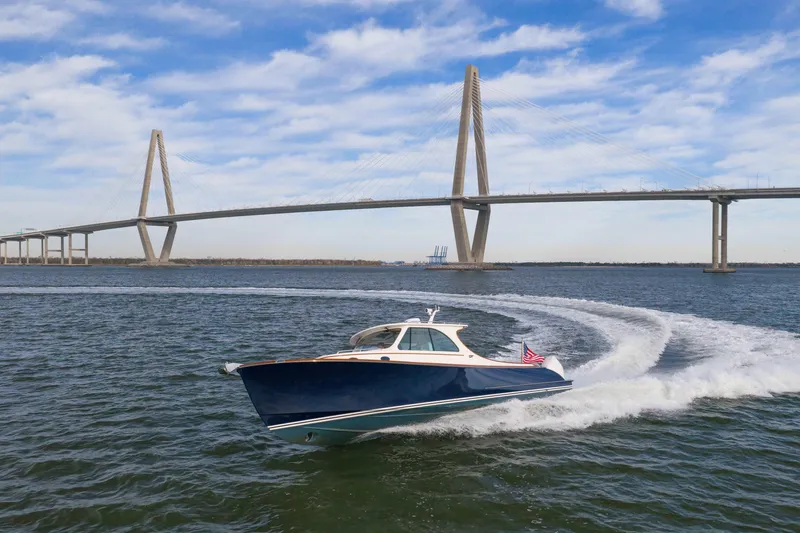 Slide: The Image of 2024 Hinckley 35 boat cruising under a large suspension bridge on a sunny day. - 2