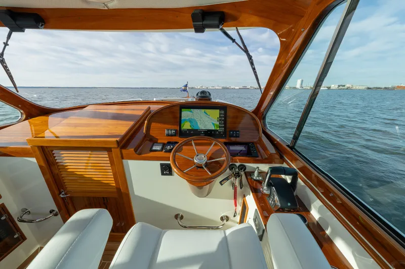 Slide: The Image of 2024 Hinckley 35 yacht cockpit with wooden dashboard and navigation screen on open water. - 20