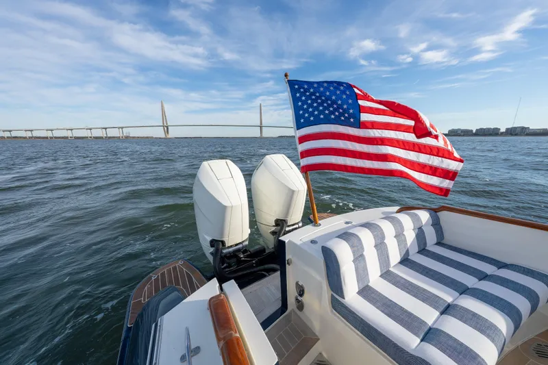 Slide: The Image of 2024 Hinckley 35 boat with American flag, striped seating, and dual engines on open water. - 33