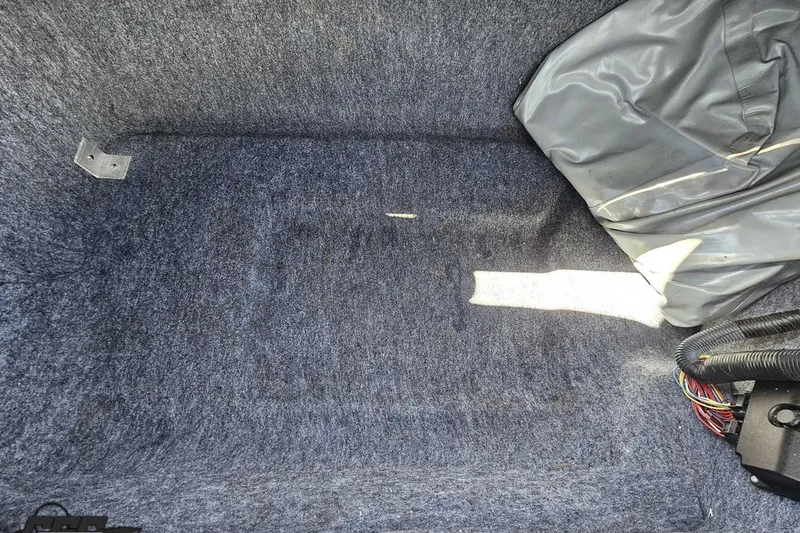 Slide: The Image of Interior storage compartment of 2017 Yamaha Boats 242X E-Series, featuring carpeted lining and wiring. - 103