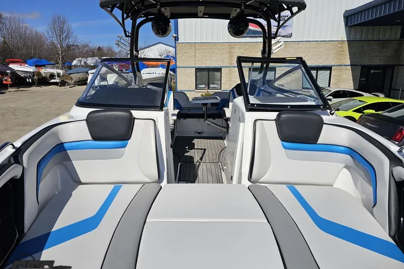 Slide: The Image of 2017 Yamaha Boats 242X E-Series interior with blue and white seating, docked outdoors. - 16