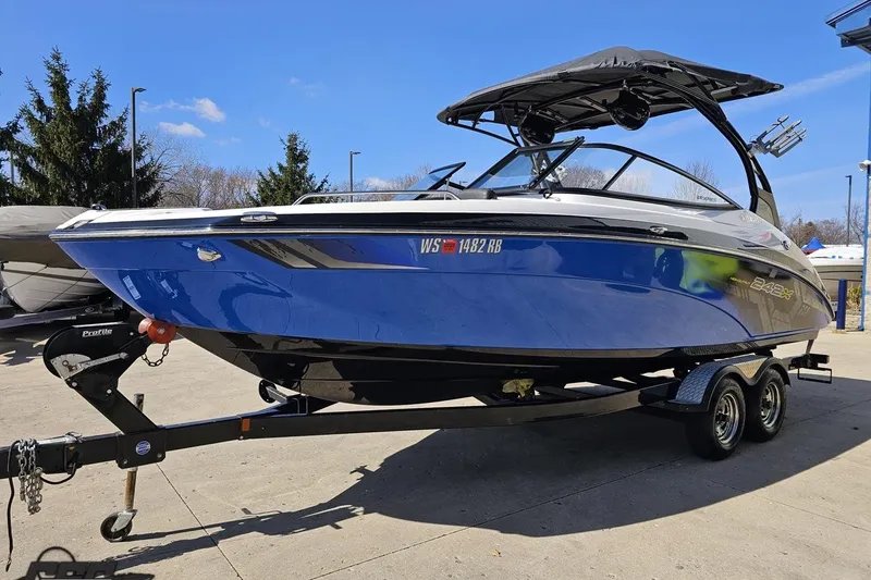 Slide: The Image of 2017 Yamaha Boats 242X E-Series on trailer, blue hull, parked outdoors. - 18