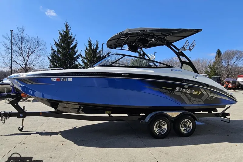 Slide: The Image of 2017 Yamaha Boats 242X E-Series in blue, parked on a trailer outdoors. - 19