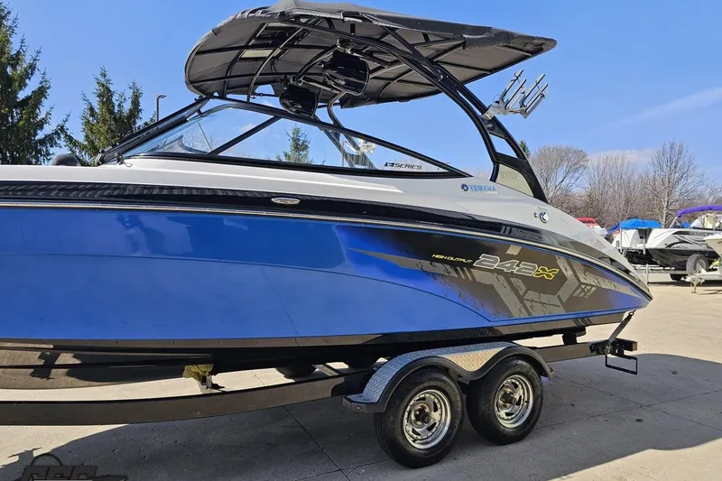 Slide: The Image of 2017 Yamaha Boats 242X E-Series in blue, parked on a trailer outdoors. - 20