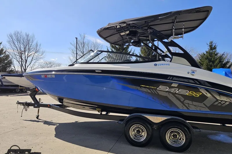 Slide: The Image of 2017 Yamaha Boats 242X E-Series in blue, parked on a trailer under clear skies. - 23
