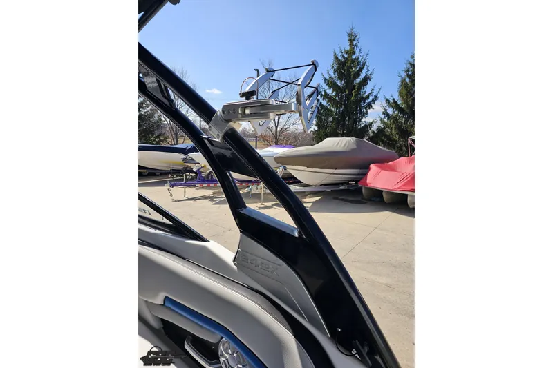 Slide: The Image of 2017 Yamaha Boats 242X E-Series interior with wakeboard rack, parked boats in background. - 48