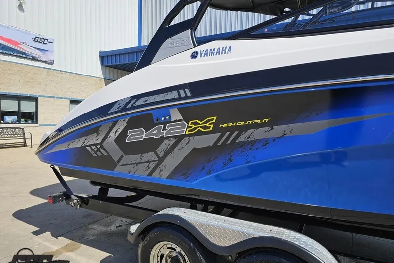 Slide: The Image of 2017 Yamaha Boats 242X E-Series, blue and white design, parked on trailer. - 5