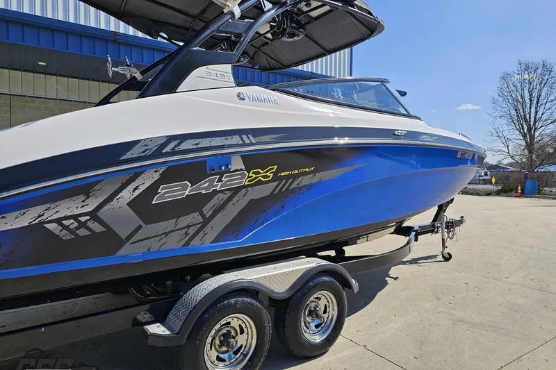 Slide: The Image of 2017 Yamaha Boats 242X E-Series on trailer, blue and white design, parked outdoors. - 8