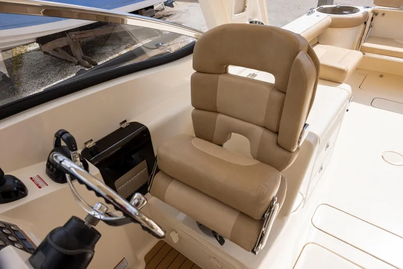 Slide: The Image of Captain's seat on 2018 Scout 275 Dorado boat, featuring beige upholstery and steering wheel. - 16
