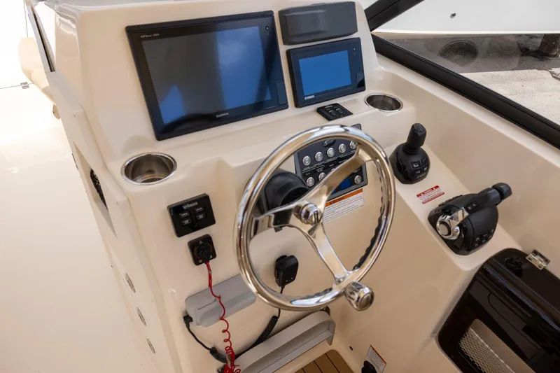 Slide: The Image of 2018 Scout 275 Dorado boat dashboard with steering wheel and navigation screens. - 17