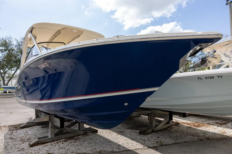Slide: The Image of 2018 Scout 275 Dorado boat on display, blue hull, parked on a trailer. - 2