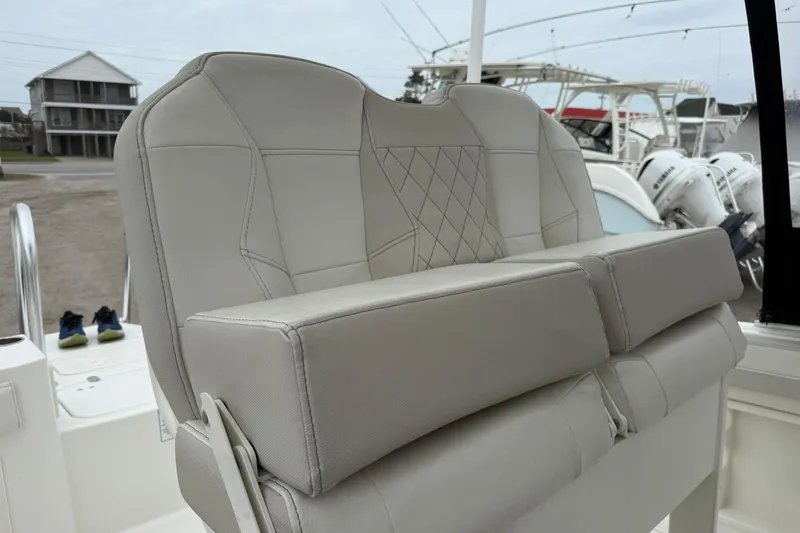 Slide: The Image of 2025 World Cat 235 TE boat seat with diamond-stitched upholstery, docked near other boats. - 14