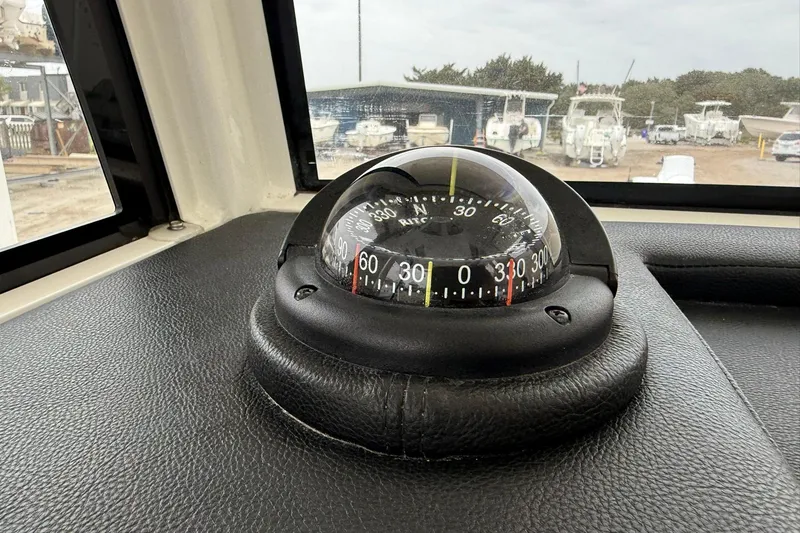 Slide: The Image of Compass on 2025 World Cat 235 TE boat dashboard, with marina view in background. - 22