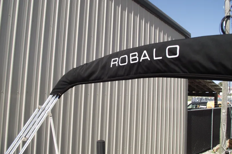 Slide: The Image of 2017 Robalo R160 Center Console boat canopy with logo, near metal building. - 23