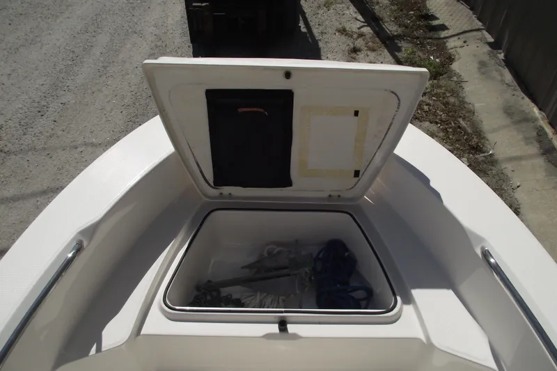 Slide: The Image of 2017 Robalo R160 Center Console boat storage compartment with open lid, containing ropes and equipment. - 7