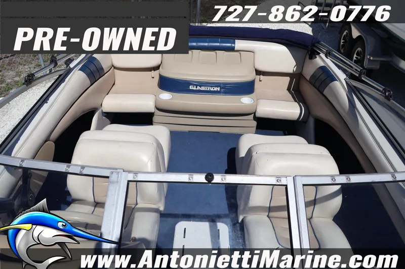Slide: The Image of Pre-owned 1997 Glastron boat interior with beige seating, blue accents, and contact information. - 8