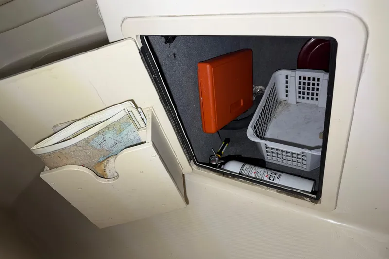Slide: The Image of Storage compartment in a 2020 Grady White Freedom 192 boat with maps and safety equipment. - 11