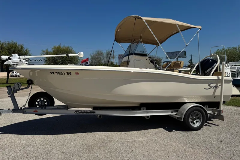 Slide: The Image of 2018 Scout 195 Sportfish boat on trailer with canopy and motor, parked outdoors. - 10