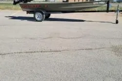 The Image of 2025 Tracker Grizzly 1436 Utility boat on trailer in parking lot. - 1