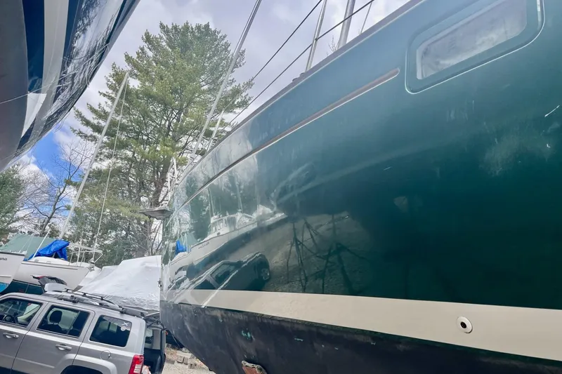 Slide: The Image of 1999 Beneteau Oceanis 381 sailboat on land, surrounded by trees and vehicles. - 20