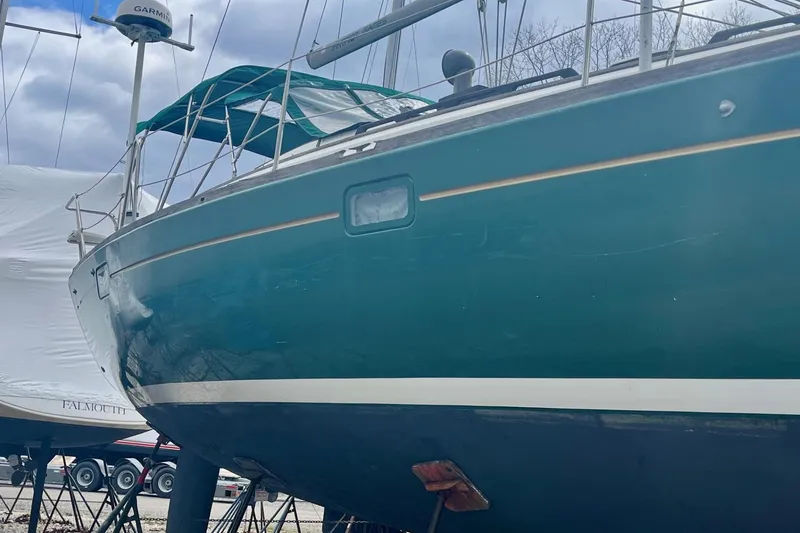 Slide: The Image of 1999 Beneteau Oceanis 381 sailboat on stands, green hull, overcast sky. - 21